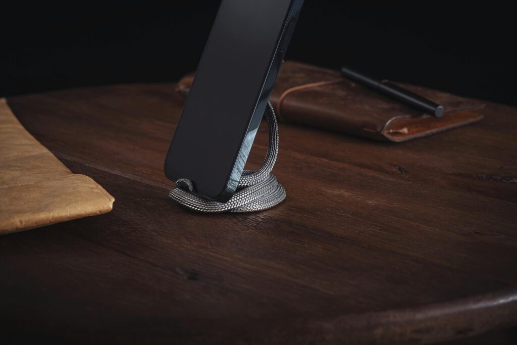 A sleek smartphone propped up by a snake figurine on a wooden desk. Sophisticated and modern.