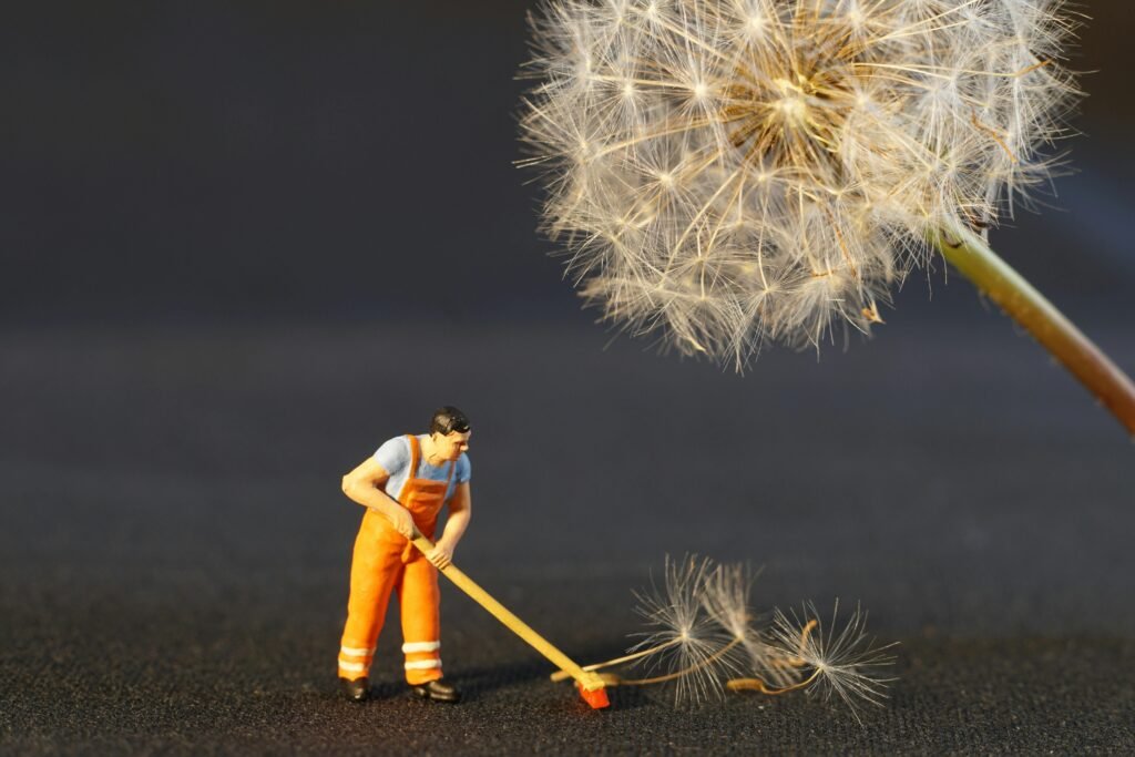 Close-up of a miniature worker figurine cleaning dandelion seeds, combining nature and toy elements.
