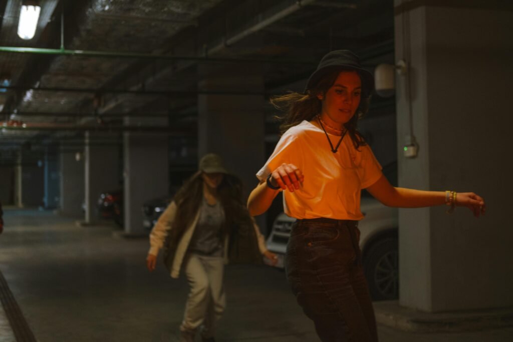 Two young women skateboarding in a dimly lit urban parking garage, showcasing style and friendship.